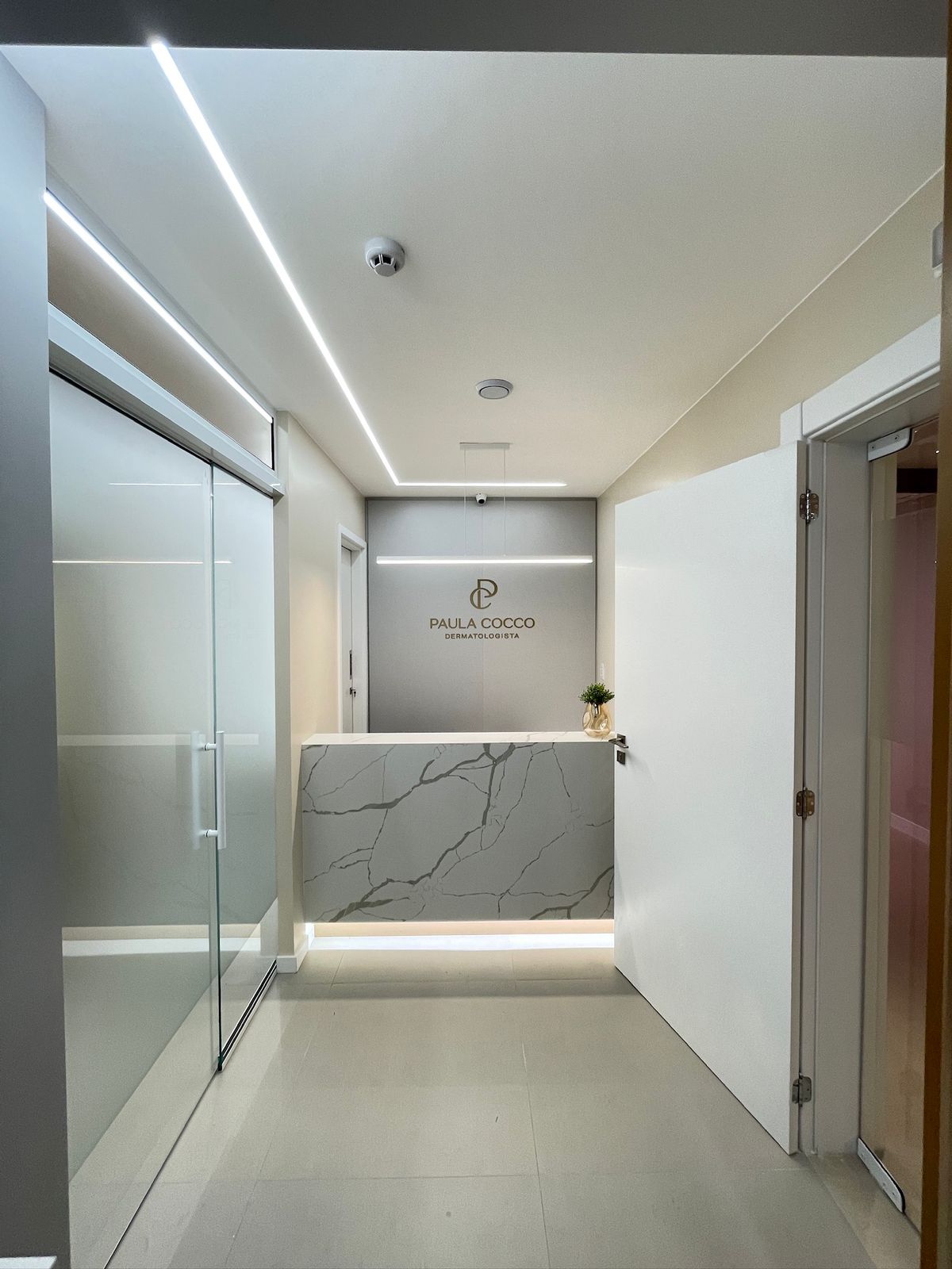 Recepção de clínica dermatologista com bancada em mármore — Líssen Arquitetura